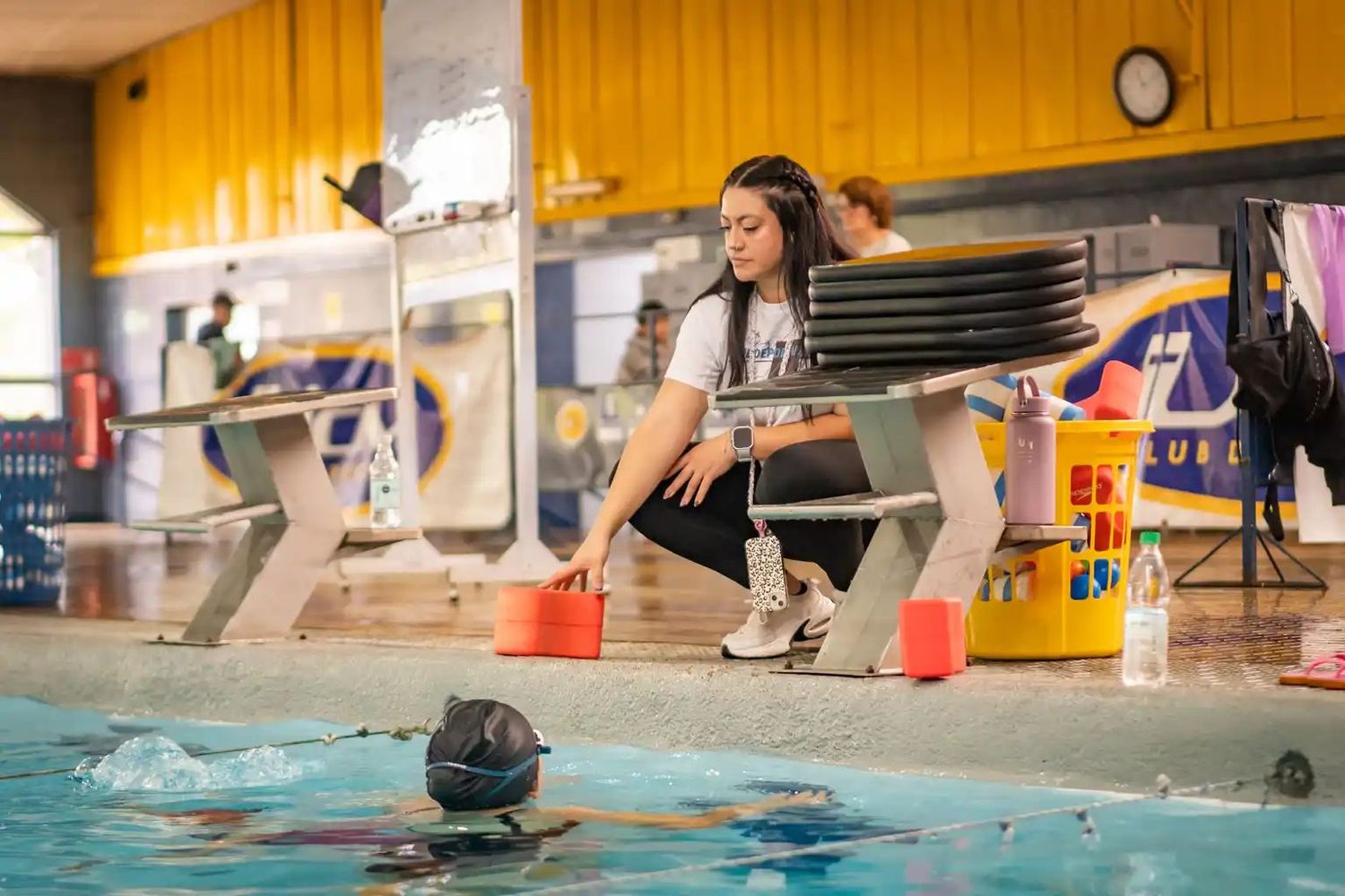 Profesora del club preparando el material de clase junto a la piscina UCM