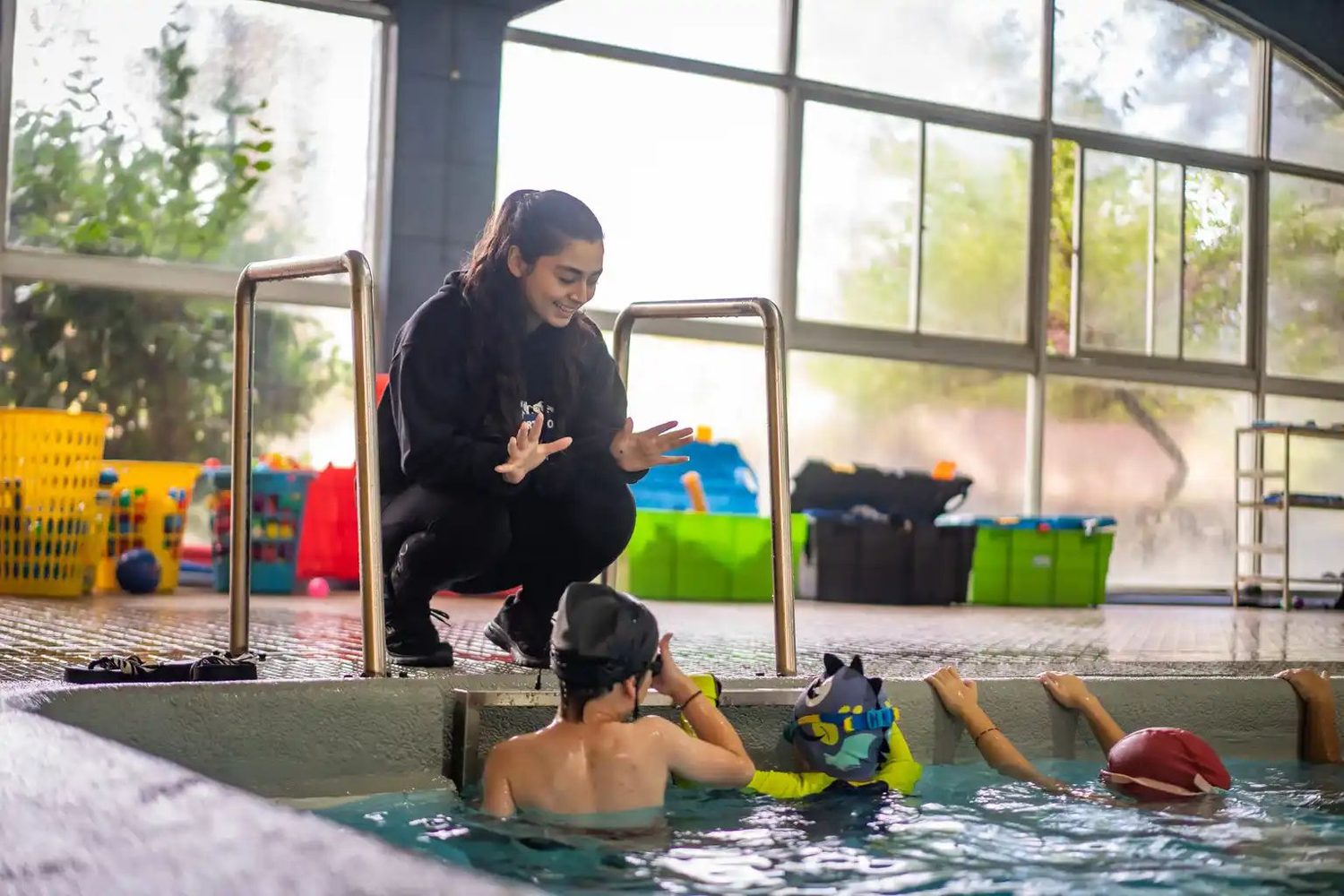 Profesora del club guiando a un grupo de niños dentro del agua