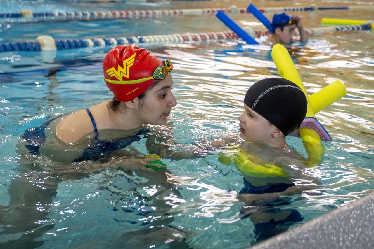 Instructora enseñando de forma personalizada a un niño dentro del agua