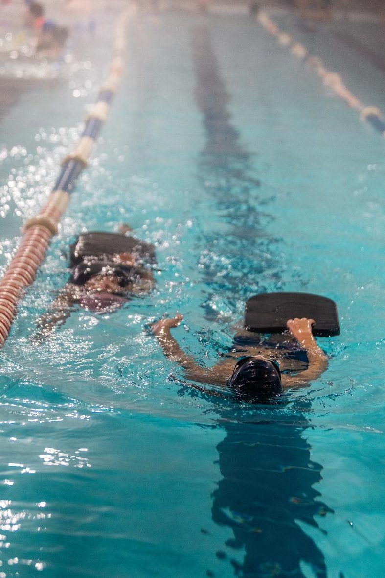 Niños entrenando con tablas de natación en la Piscina Temperada UCM durante una clase del programa de inclusión